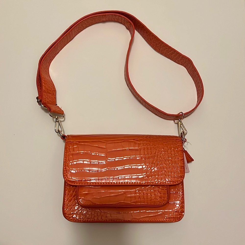 Coral bag with adjustable strap. Never worn but has 2 minor tears on the inside